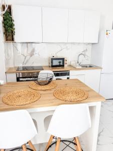 a kitchen with white cabinets and a wooden table with white chairs at Nido del Sol in Guía de Isora