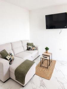 a white living room with a couch and a table at Nido del Sol in Guía de Isora