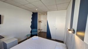 a bedroom with a white bed and a blue wall at Hotel Le Rohu Vannes in Séné