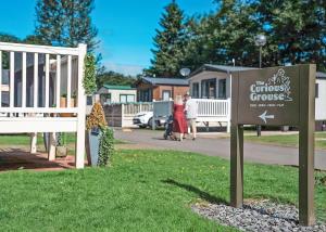 a sign in the grass next to a house at Heather View Holiday Park in Stanhope