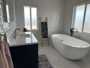 a white bathroom with a tub and a sink at The View Villa in Hartswell +7 photos