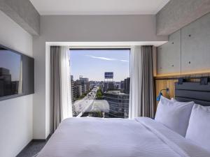 a bedroom with a bed and a large window at ibis Styles Nagoya in Nagoya