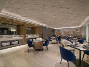 a dining room with tables and blue chairs at Mercure Surabaya Manyar in Surabaya