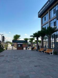 a building with benches and palm trees in front of it at Polaris resort in Almaty