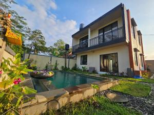 a swimming pool in front of a house at Kala Senja Guest House in Sukawati