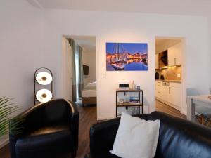 a living room with a black leather couch and a kitchen at Ohlerich Speicher App_ 19 in Wismar