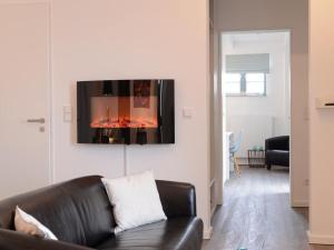 a living room with a black leather couch and a fireplace at Ohlerich Speicher App_ 19 in Wismar