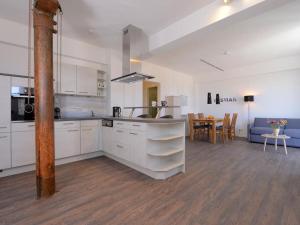 a kitchen with white cabinets and a living room with a table at Ohlerich Speicher App_ 10 in Wismar