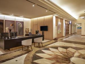a lobby with a desk with chairs and a television at Mercure Ambassador Jeju in Seogwipo