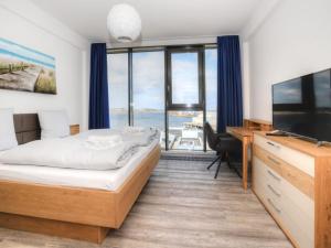 a bedroom with a bed and a television and a desk at Ohlerich Speicher App_ 46 in Wismar +34 photos
