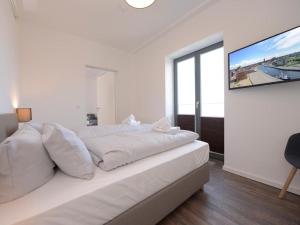 a white bedroom with a large bed and a tv at Ohlerich Speicher App_ 27 in Wismar +13 photos