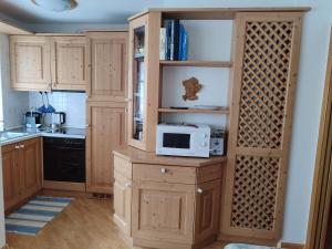 a kitchen with wooden cabinets and a microwave on a counter at Appartamento Campitello House in Campitello di Fassa