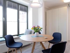 a dining room with a table and chairs and a vase with flowers at Ohlerich Speicher App_ 14 in Wismar