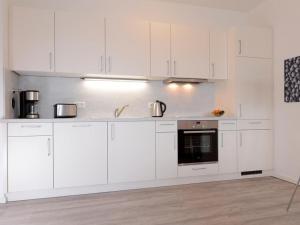 a white kitchen with white cabinets and appliances at Ohlerich Speicher App_ 14 in Wismar
