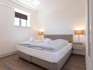 a white bedroom with a large bed with white sheets at Ohlerich Speicher App_ 10 in Wismar
