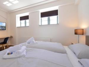 a white bedroom with two beds and two windows at Ohlerich Speicher App_ 10 in Wismar +12 photos