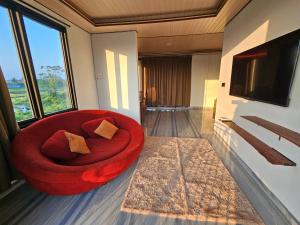 a red chair in a living room with a tv at Kala Senja Guest House in Sukawati