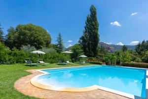 a swimming pool in a yard with chairs and umbrellas at Borgo San Valentino in Arrone