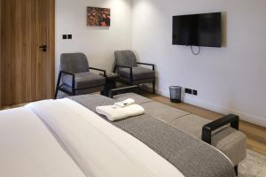 a bedroom with a bed with two chairs and a flat screen tv at Black Muse Residence in Benin City +12 photos