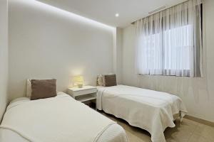 two beds in a white room with a window at Antika Marbella 1A in Marbella