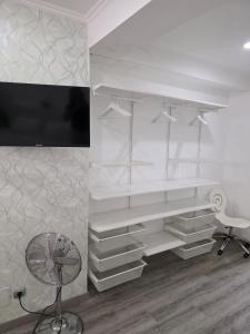 a room with white shelves and a tv and a chair at Mikaela Guest House in Odivelas