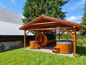 a wooden gazebo with a table and two drums at U Stocha - Jacuzzi & sauna - dom dla 13 osób in Poronin