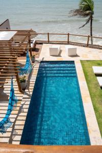 a swimming pool with two chairs and the ocean at Fran de Fransquinha in Taíba +10 photos