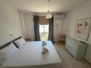 a bedroom with a white bed and a dresser and a window at Riana Latchi Apartment in Polis Chrysochous +13 photos