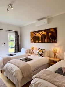 ein Schlafzimmer mit drei Betten und einem Gemälde an der Wand in der Unterkunft Langholm Hotel in Walvis Bay