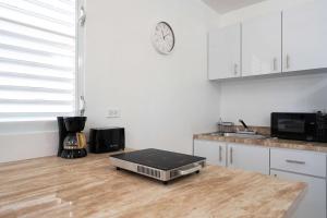a kitchen with a clock on the wall and a microwave at Colmado by Otium in Hato Candal