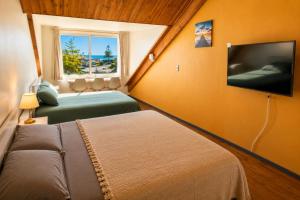 a bedroom with two beds and a flat screen tv at Hostal Boutique F in El Quisco