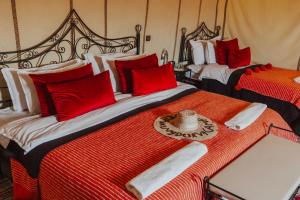 two beds in a room with red and white at Kidal Luxury Camp in Adrouine +17 photos