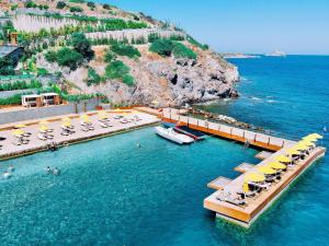 a dock with chairs and umbrellas in the water at The Bodrum Hotel Yalıkavak - MGallery Collection in Yalıkavak