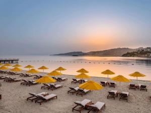 a group of chairs and umbrellas on a beach at The Bodrum Hotel Yalıkavak - MGallery Collection in Yalıkavak