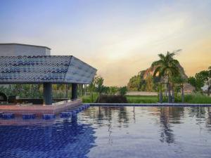 a pool at a resort with a mountain in the background at Pullman Lombok Merujani Mandalika Beach Resort in Kuta Lombok