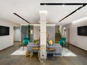 a lobby with a couch and chairs and a tv at Mercure Tokaj Center in Tokaj