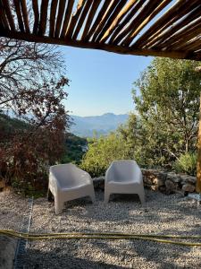 two white chairs sitting on a patio with a view at Charmant chalet en montagne in Petreto-Bicchisano
