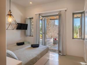 a bedroom with two beds and a sliding glass door at Villa Ena - Beach getaway in Logaras