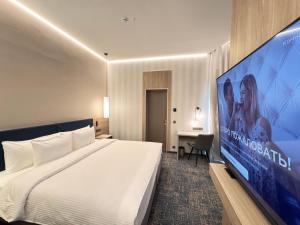 a hotel room with a large bed and a large screen at West Plaza Hotel in Oral