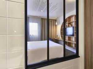 a mirror in a room with a bed and a tv at ibis Styles La Roche-sur-Yon in Mouilleron-le-Captif +225 photos