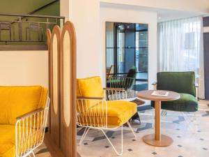 a waiting room with yellow chairs and a table at Le Splendid Hotel Lac D'Annecy - Handwritten Collection in Annecy