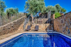a pool with two chairs next to a stone wall at Casa rural rio yeguas in Azuel