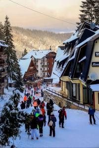 a group of people walking in the snow near buildings at Lunara Vlasic in Vlasic