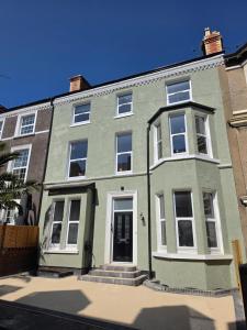a green house with a white door on a street at Fox House Llandudno in Llandudno