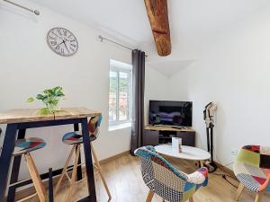 a living room with a table and a clock on the wall at Le Montgy - Studio tout confort à Royat National N1 in Royat