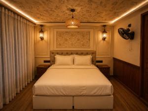 a bedroom with a bed and two lights and a ceiling at Kerala Boat Trips in Kumarakom