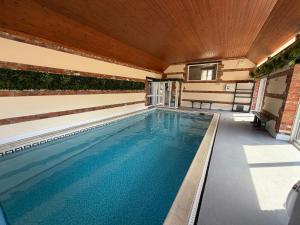 an indoor swimming pool with a wooden ceiling at Stable Cottage with pre booked use of Indoor Swimming Pool in Frome