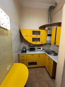 a small kitchen with yellow cabinets and a sink at Monro in Odesa
