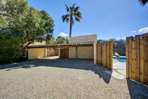 a garage with a fence and a palm tree at Le Mas Des Brunes in Saint-Laurent-dʼAigouze