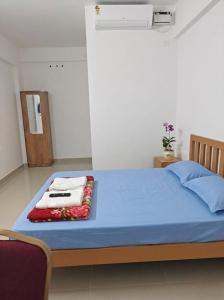 a bedroom with a blue bed with two towels on it at Uthram Avenue in Tāmarakulam +1 photo